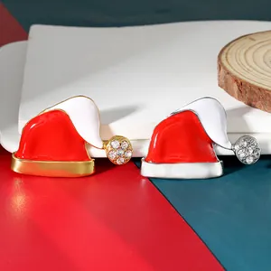 Detail of red enamel Christmas hat brooches with rhinestones on a festive background