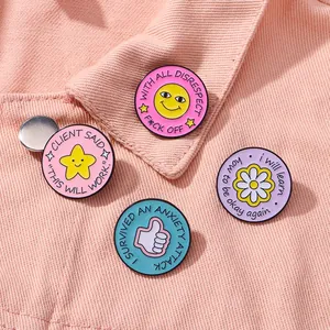 Detail van vier kleurrijke emaille pins met grappige Engelse teksten op roze spijkerstof