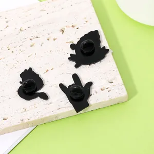 Schwarze Emaille-Pins Kollektion mit Gummikupplung auf Stein und grünem Hintergrund