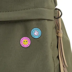 Macro detail van emaille badges met smiley en duim omhoog op een canvas tas