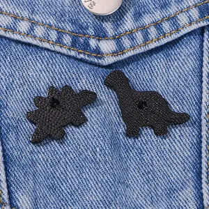 Set di spille a forma di dinosauro nero su denim con dettagli della texture posteriore e gomma