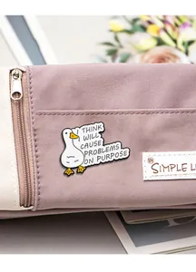 Detailed view of a white enamel duck pin with a funny slogan on a purple canvas bag