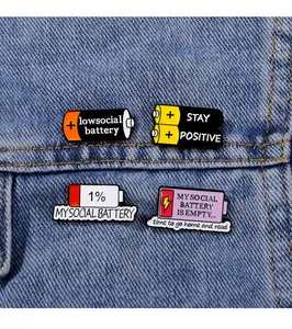Close-up of funny battery enamel pins showing social battery levels on denim fabric