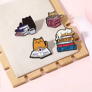 Detail of four creative cat and book enamel pins in a tray with soft pink background