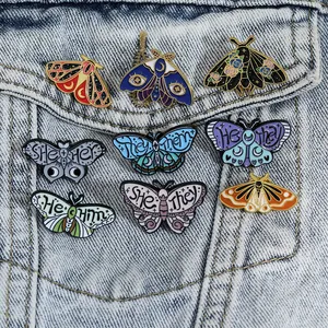 Set of 8 butterfly enamel pins with pronouns on a blue denim jacket pocket
