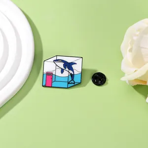 Macro detail of enamel pin showing a creative killer whale in a glass tank with ROOM door