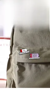 Detail showing two social battery enamel pins on canvas bag with creative status text