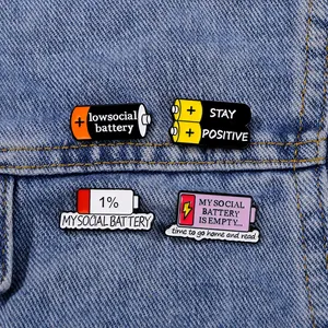 Battery themed enamel pin set on denim jacket featuring stay positive and social battery art