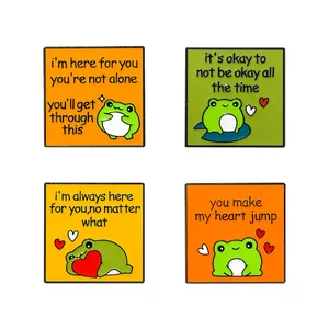 Set of four green frog enamel pins with inspirational quotes on square metal badges
