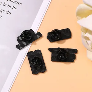 Set of 4 black plated metal brooch pins with textured hexagonal back on a stylish background