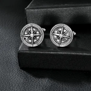 Detail of vintage silver compass cufflinks with central crystal on black leather background