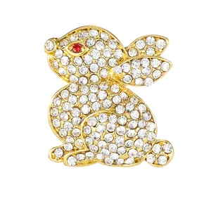 Goldene Hasen-Brosche mit weißen Kristallen und einem roten Strass-Auge auf weißem Grund