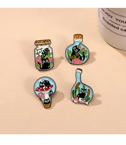 Détail de quatre épingles en émail de chat noir avec des plantes sur fond beige chaud