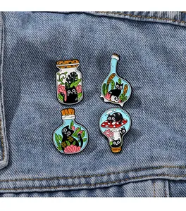 Détail de quatre épingles en émail de chat en bouteilles sur tissu denim bleu