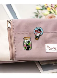 Détail de pins chat noir en bouteille et ampoule sur un sac en toile violette