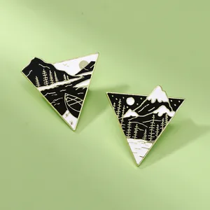 Close-up of black and white enamel triangle badges with gold mountain and river patterns