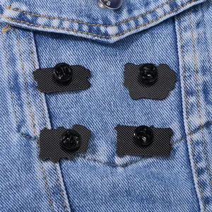 Set di quattro chiusure per spille in metallo nero esposte su una giacca di jeans blu