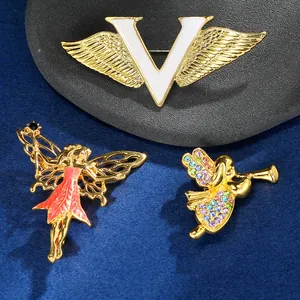 Detail van drie creatieve emaille broches met vleugels en strassteentjes op blauwe basis