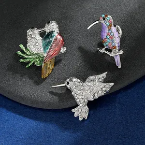 Vue détaillée des broches perroquet en émail coloré et colibri en strass étincelants