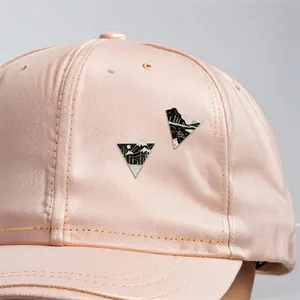 Minimalist triangle shield enamel pins featuring mountain and forest scenes on a cap