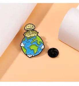 Détail d'une broche en émail représentant la Terre avec champignon atomique et fermoir papillon