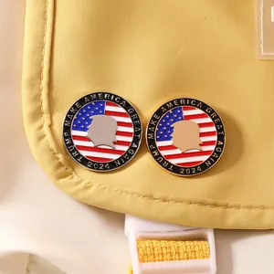 Detail of Trump 2024 enamel pins with American flag design on a yellow fabric bag