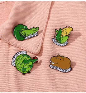 Detailed view of four creative enamel pins featuring cute animal-vegetable puns on fabric