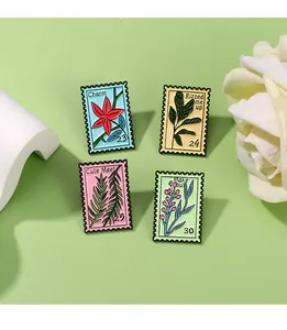 Detail view of four floral enamel pins with stamp edges on a soft green background