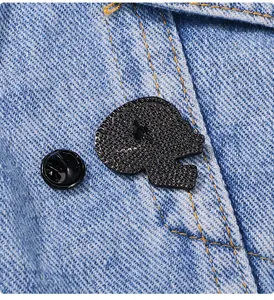 Dettaglio macro del retro della spilla in lega nera con chiusura a farfalla su denim