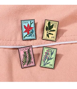 Detail of four stamp-shaped enamel pins featuring flower patterns and phrases on fabric