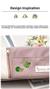Detail of broccoli crocodile and artichoke hen enamel pins on a purple canvas bag