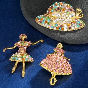 Detailed view of rhinestone ballerina and sun hat brooches on blue textured fabric