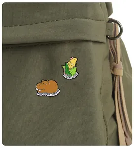 Detail of enamel hippopotamus and hamster corn badges pinned on a green canvas bag