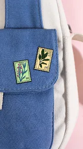 Detail of floral stamp enamel pins with floral patterns on a canvas bag accessory