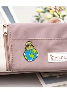 Détail du pin's en émail terre de dessin animé avec nuage sur sac en tissu violet