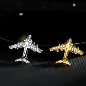 Broches d'avion élégantes dorées et argentées avec strass sur un fond noir texturé