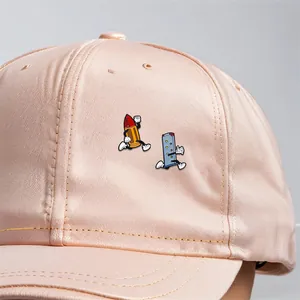 Detailed view of apricot satin baseball cap with running cartoon bullet and magazine print