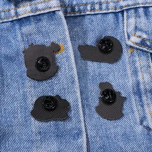 Back view of cartoon pins with four black butterfly clasps on blue denim fabric