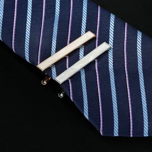 Detail of rose gold and silver tie clips with shell inlay on a blue striped tie