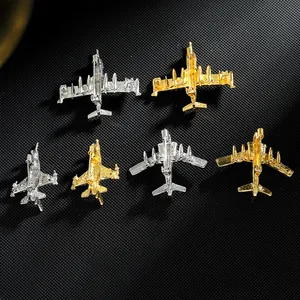 Détail de diverses broches en forme d'avion dorées et argentées sur fond noir