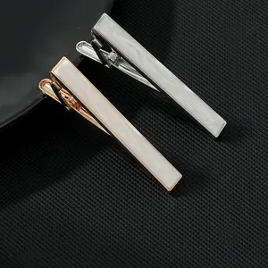 Close-up of gold and silver business tie clips with white marble inlay for men