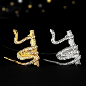Macro di spille a serpente in oro e argento con strass bianchi su texture in legno