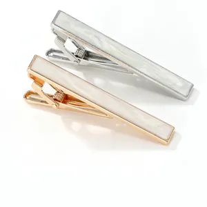 Detailed macro view of gold and silver tie clips with white mother of pearl inlay texture