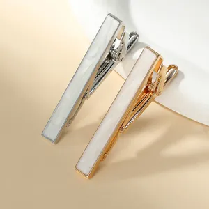 Close-up of gold and silver tie clips with white mother of pearl inlay for men