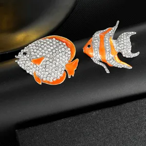 Macro shot of silver tropical fish brooches with orange enamel and sparkling rhinestones