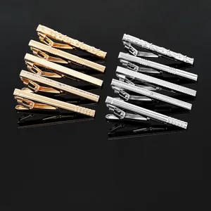 Detailed close-up of ten metallic tie clips in silver and gold with various textures