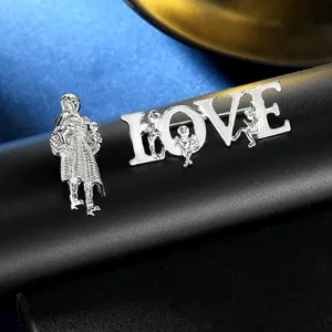 Detailansicht der silbernen LOVE-Brosche und Figuranstecker auf edlem Samthintergrund