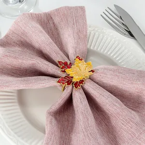 Close-up of golden maple leaf napkin ring with red enamel on elegant table setting