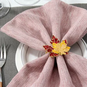Detail of colorful maple leaf napkin ring with enamel finish on a beige linen napkin