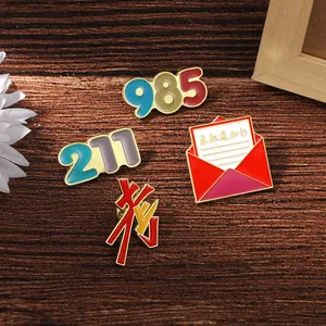 Macro detail of enamel exam lapel pins showing 985 and 211 motifs on wood background
